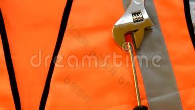 橙色施工背心上有螺丝刀、施工工具、量尺、扳手、劳动节概念